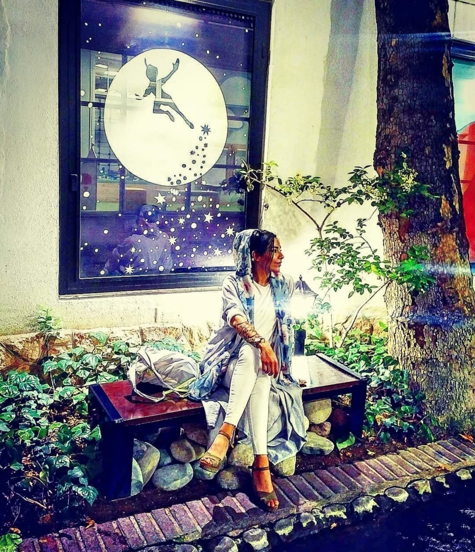 Gründerin Atussa sitzt auf einer Bank. Hinter Ihr befindet sich ein abstraktes Gemälde.