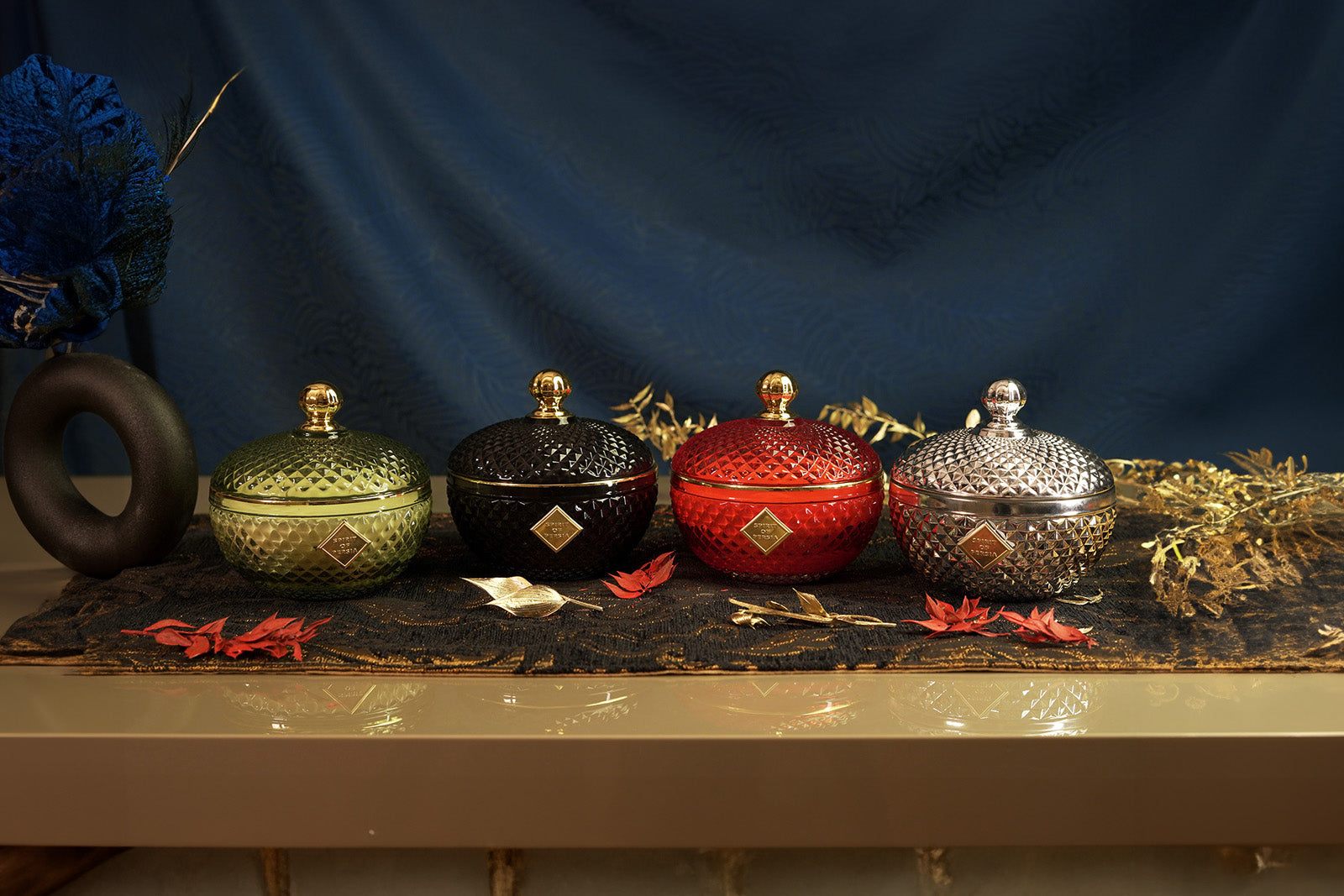 Unsere hochwertigen vier Duftkerzen der Kollektion „Magic od Meditation" stehen nebeneinander auf einem orientalisch dekorierten Tisch.
