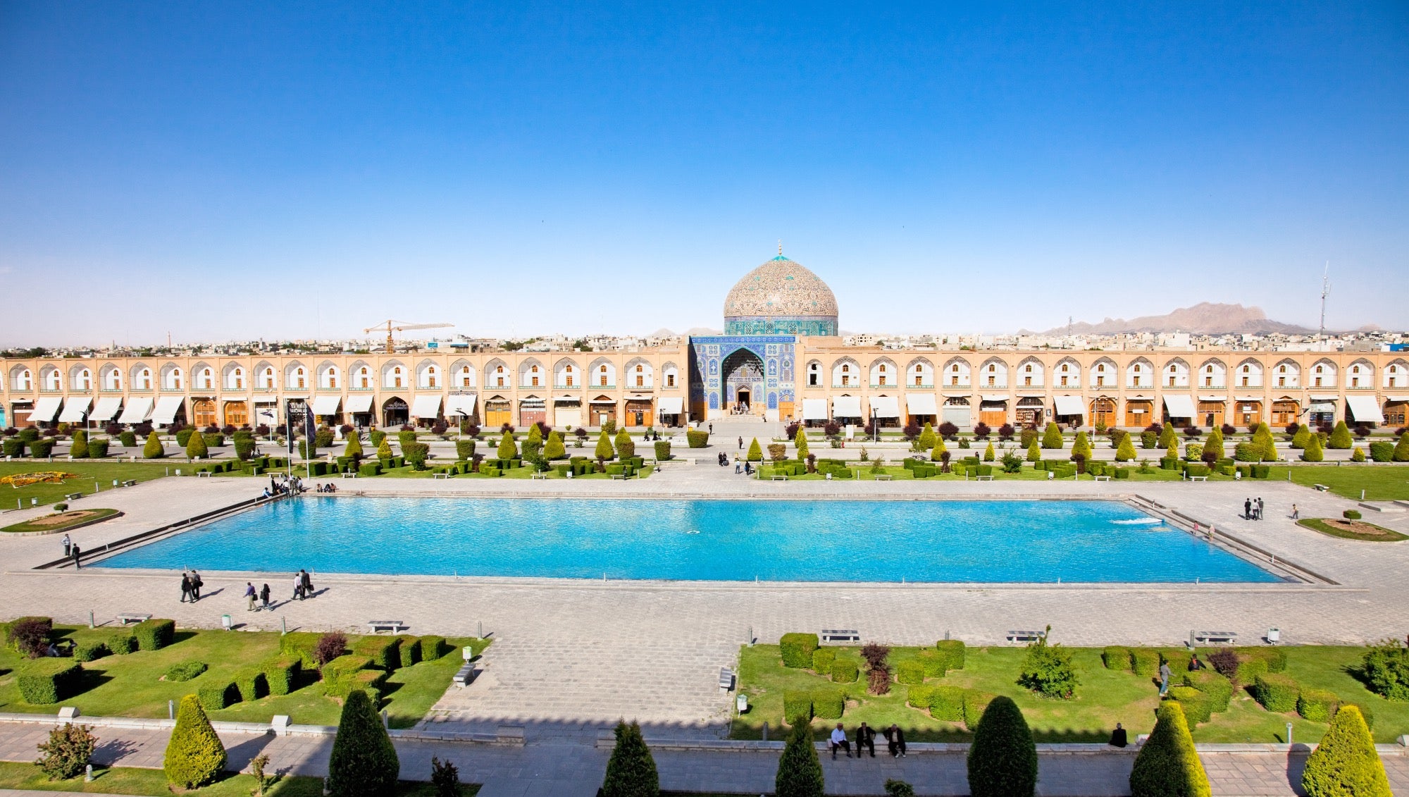 Das Stadtbild von Isfahan aus der Vogelperspektive. Im Vordergrund ist ein himmelblauer Teich.